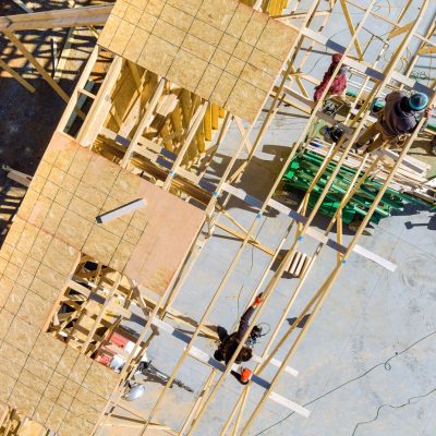 Building contractor carpenter placing new building wood engineered trusses on a residential under construction