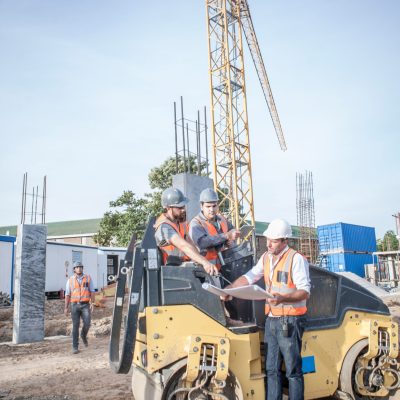 Site manager talking with drivers about blueprint on construction site